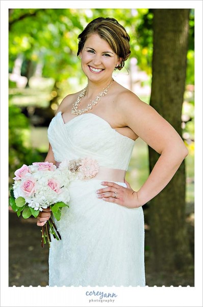 bride with lace gown and pink rosette belt