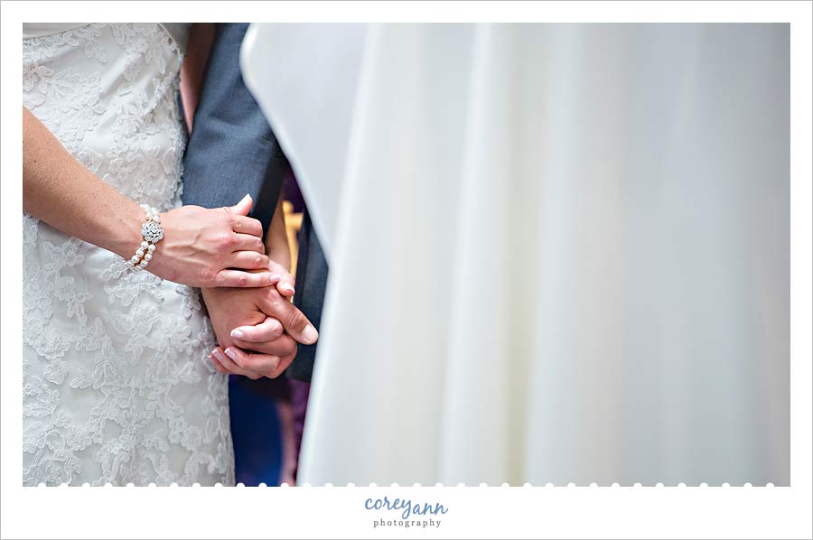 bride and groom holding hands during wedding ceremony in ohio