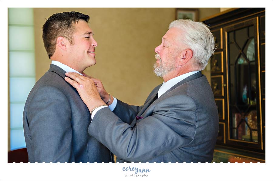 grooms father helping him get ready for the wedding