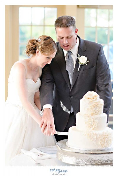 cutting wedding cake by west side bakery at portage country club