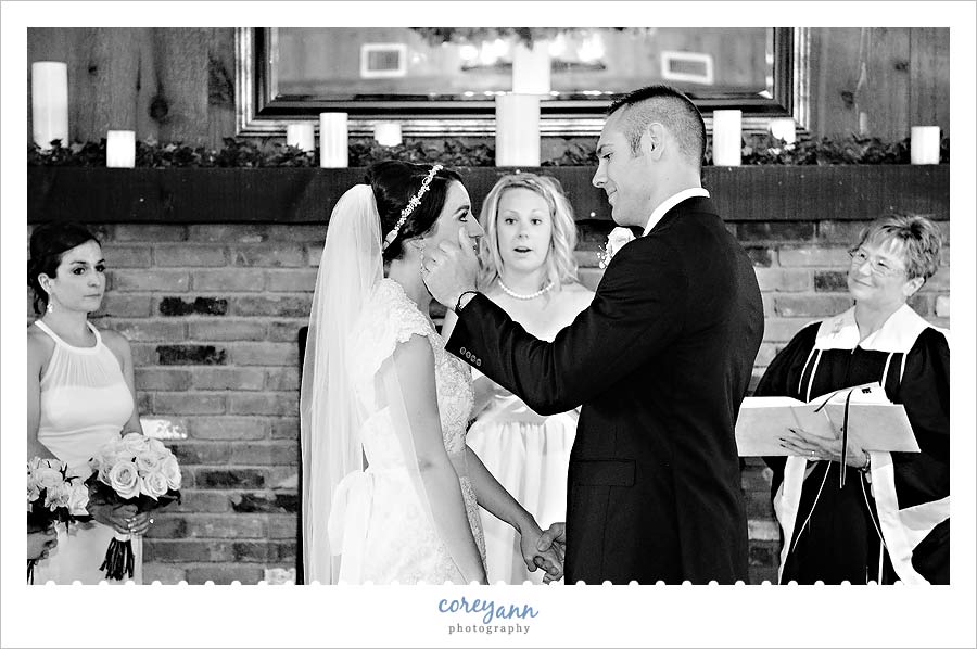 groom wiping tear from bride's cheek during ceremony