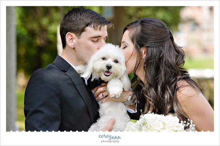 bride and groom kissing their dog on their wedding day