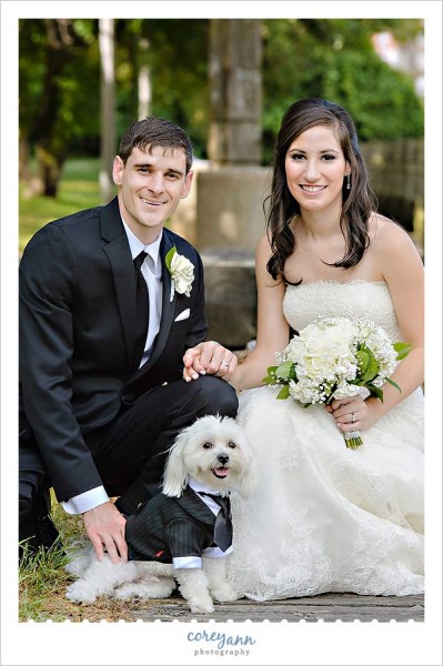 posed picture of bride and groom with their dog in a tux