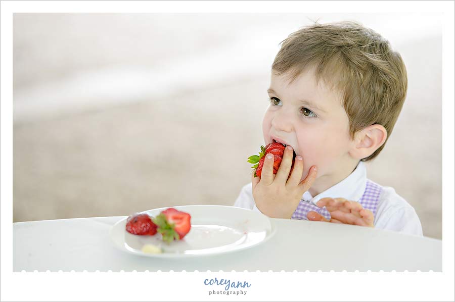 child eating a strawberry while wearing a bowtie