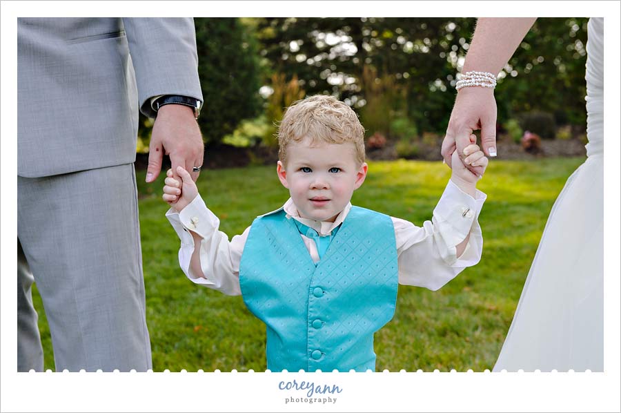 bride and groom holding son's hands