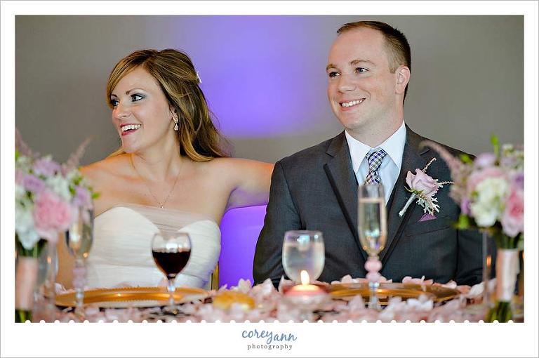 bride and groom at pink and gold sweetheart table during wedding reception