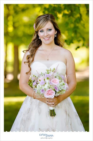 bride with long curly hair and pink and purple bouquet outside in august in ohio