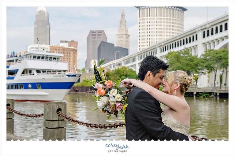 bride and groom with cleveland skyline and goodtime boat