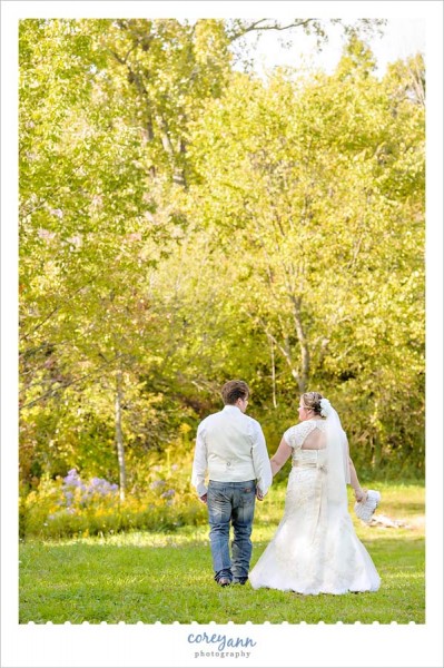 bride and groom walking through field at farm in ohio