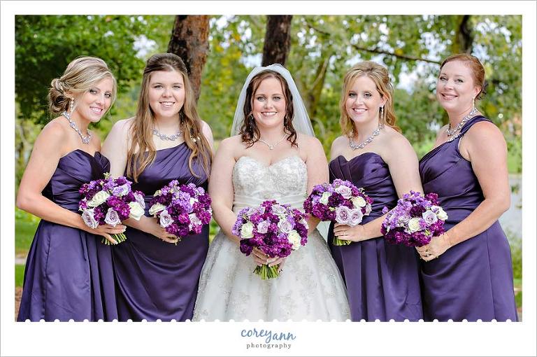 bridesmaids in various purple dresses with mixed purple floral bouquets
