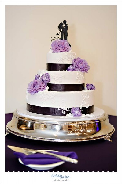 white and purple wedding cake with silhouette cake topper