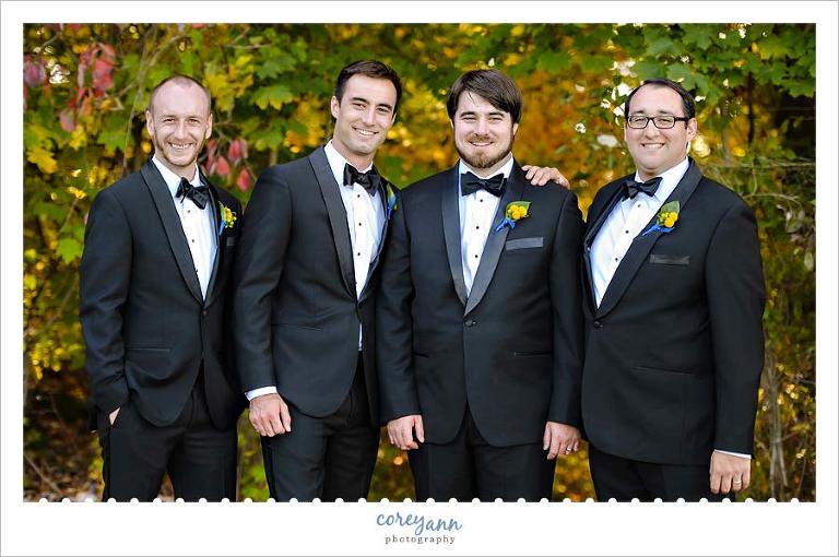 groom and groomsman in black suits with bow ties
