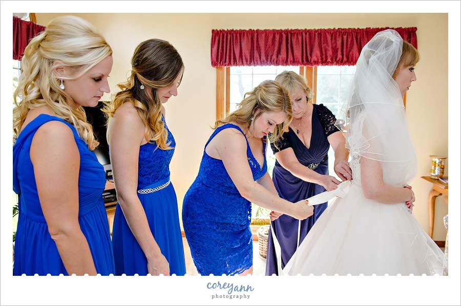 bride and brides mom helping bride get dressed before wedding