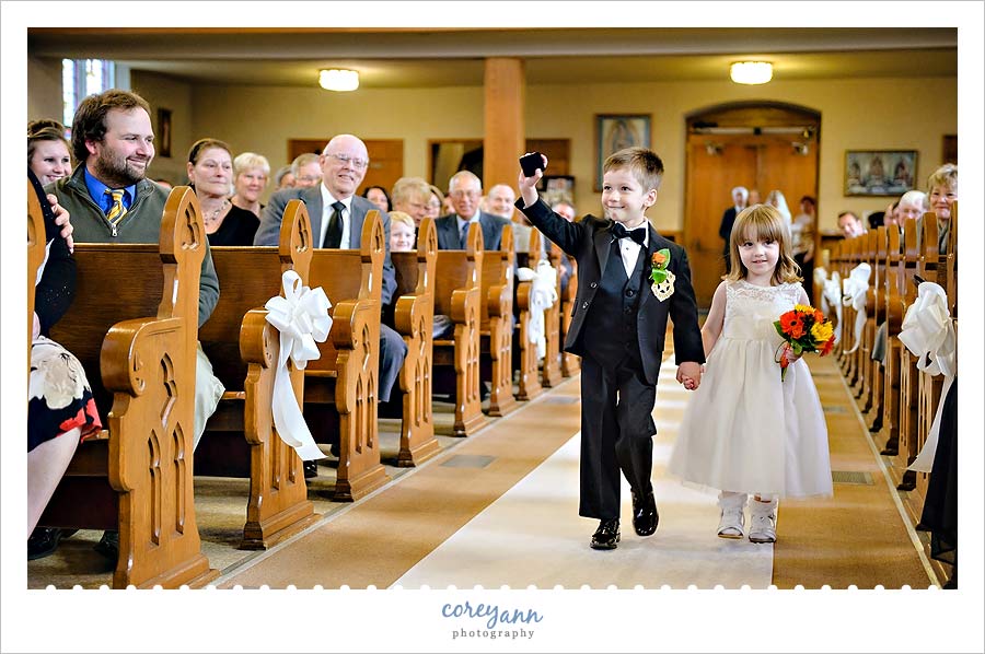 ring bearer showing off ring box while walking down the aisle