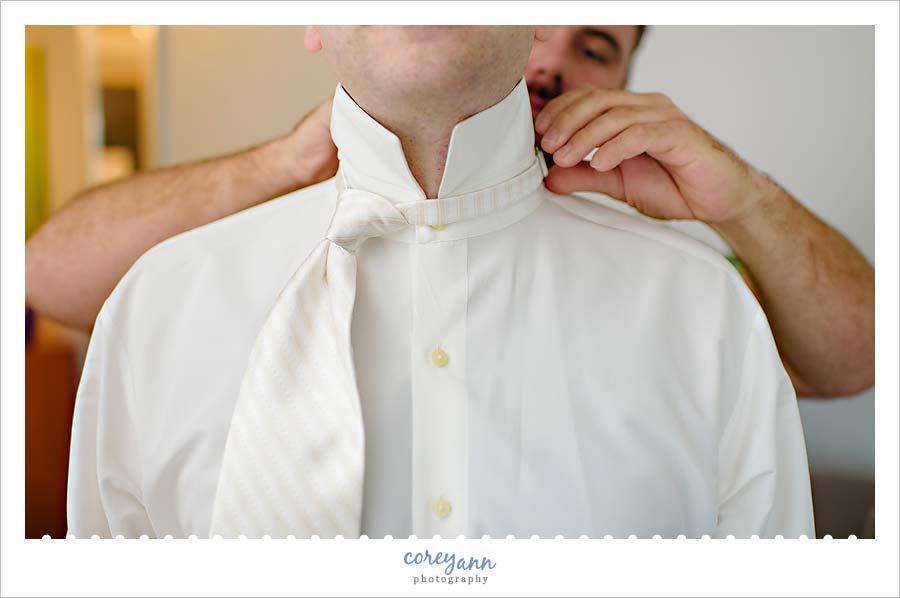 grooms tie being put on before wedding ceremony