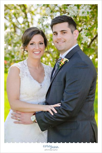 Bride and groom in front of blossoming fruit tree in Ohio