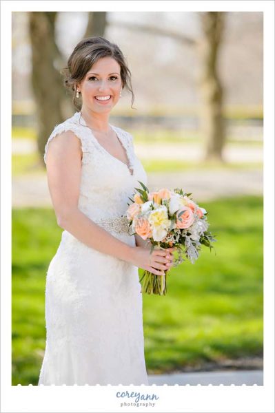 Bride in a lace gown holding a peach wedding bouquet in Ohio