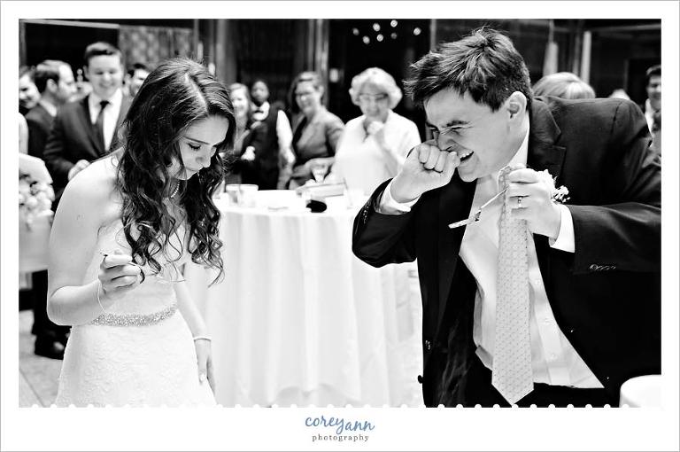Groom laughing after dropping cake on bride during cake cutting