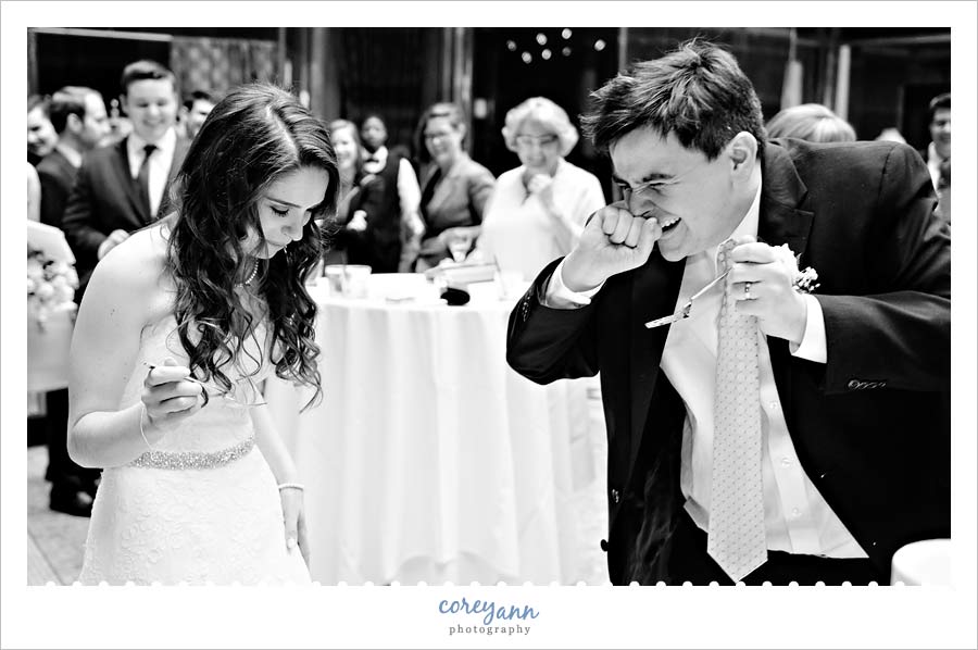 Groom laughing after dropping cake on bride during cake cutting