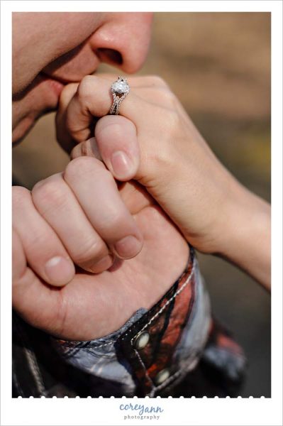 Man kissing hand of fiancee with engagement ring shown