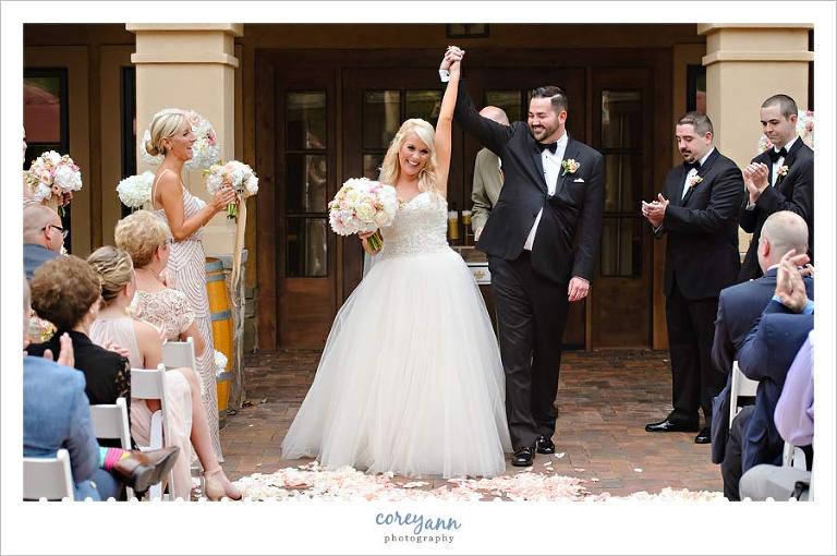 Bride and groom raising their arms after wedding ceremony