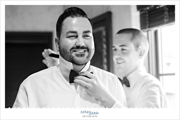 Groomsman helping with tie on Groom in Canton