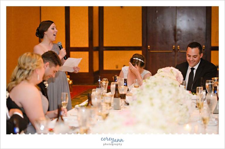 Bride and groom laughing during toast at wedding reception
