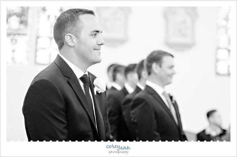 Groom smiling when seeing bride coming down aisle