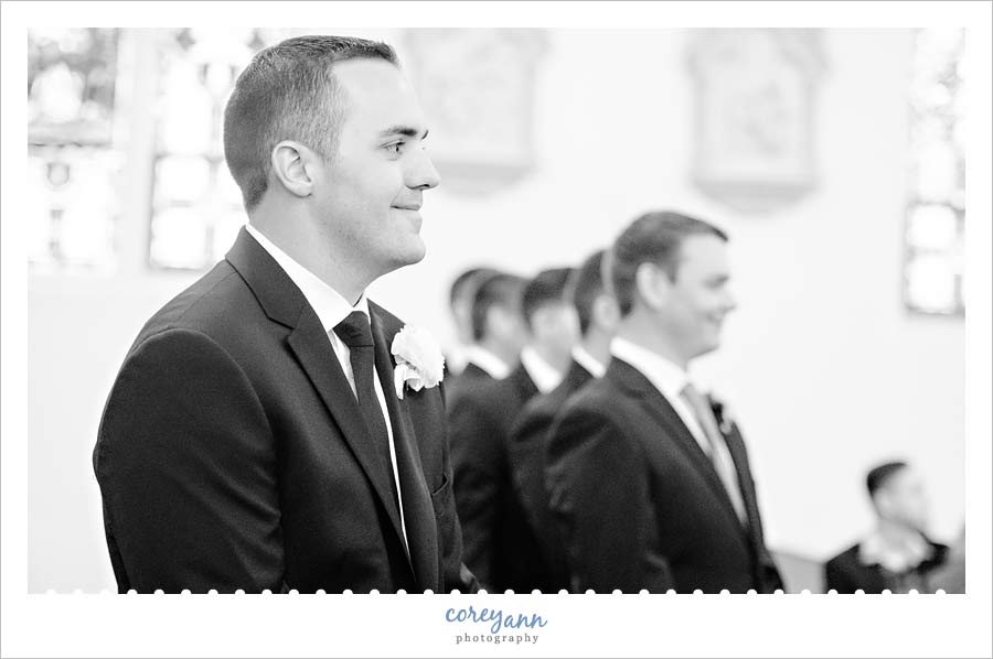Groom smiling when seeing bride coming down aisle
