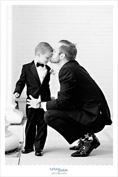 Groomsman kissing his son the ring bearer before wedding ceremony
