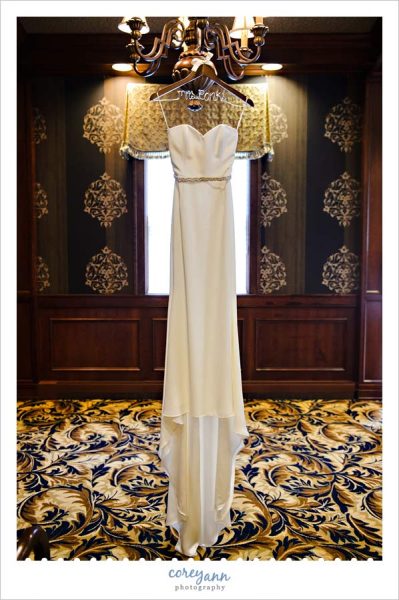 wedding dress hanging on custom hanger from light fixture