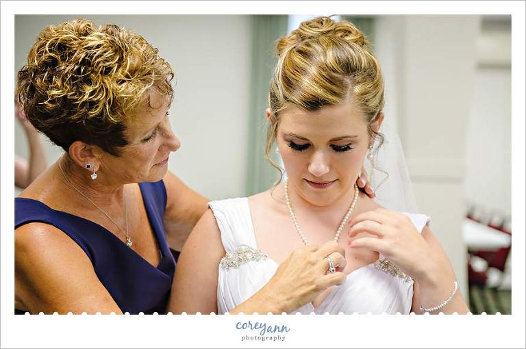 mother of bride helping bride get ready for wedding