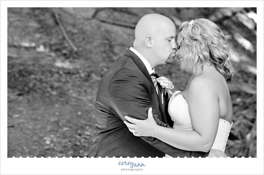 Groom kissing bride's nose in park