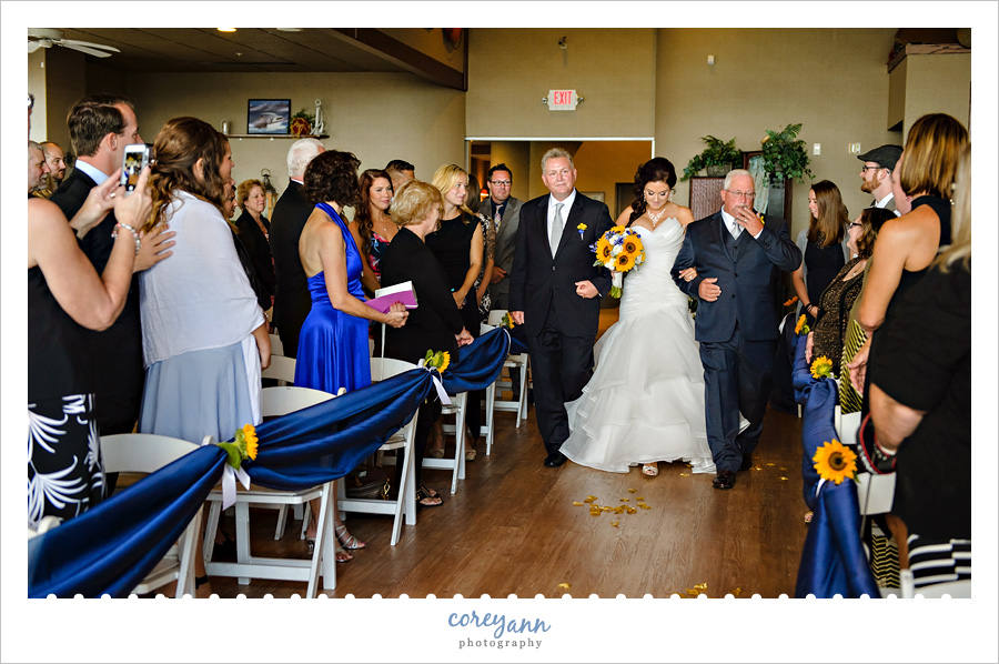 bride walking down aisle by dad and stepdad