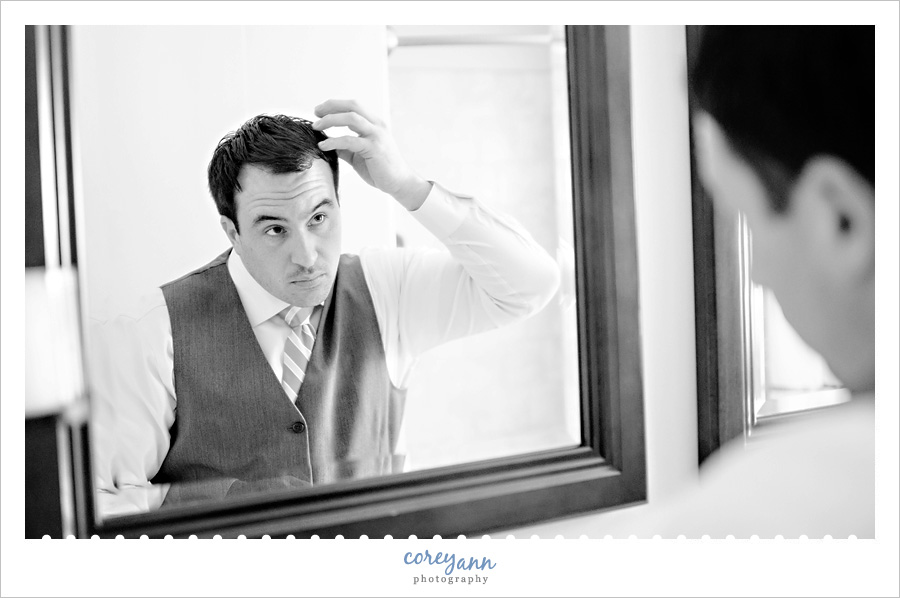 groom fixing hair while getting ready for wedding 