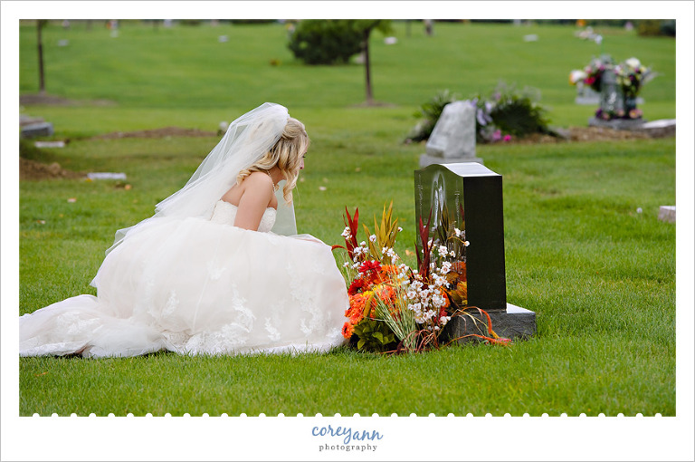 bride leaving bouquet at sisters grave after wedding