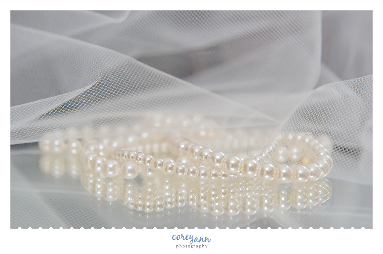 Wedding pearls sitting on a mirror with veil