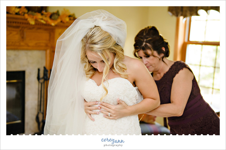 bride getting dressed while her mom helps her