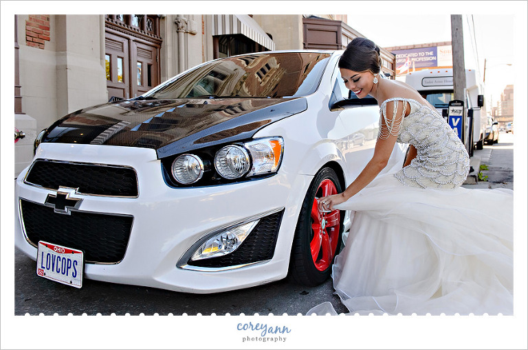 Bride cleaning wheel of racecar with her wedding dress