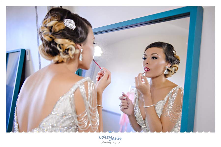 Bride putting on lipstick before first look 