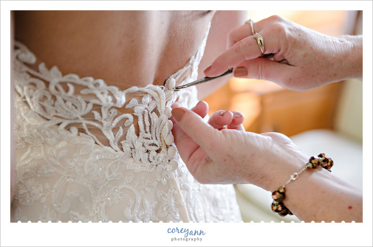 Bride's mother using button hook to do buttons on wedding dress