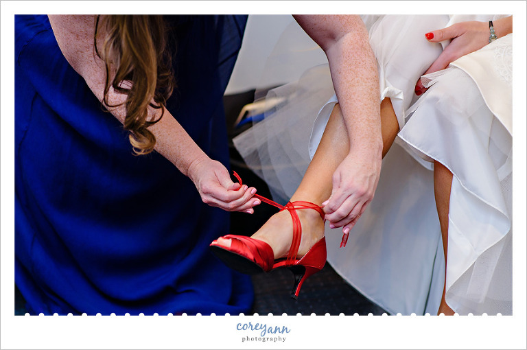 Bride's sister putting shoes on bride in Cleveland