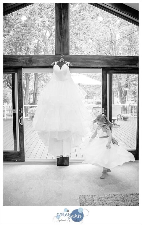 Bridal gown hanging with flower girl dancing beside it