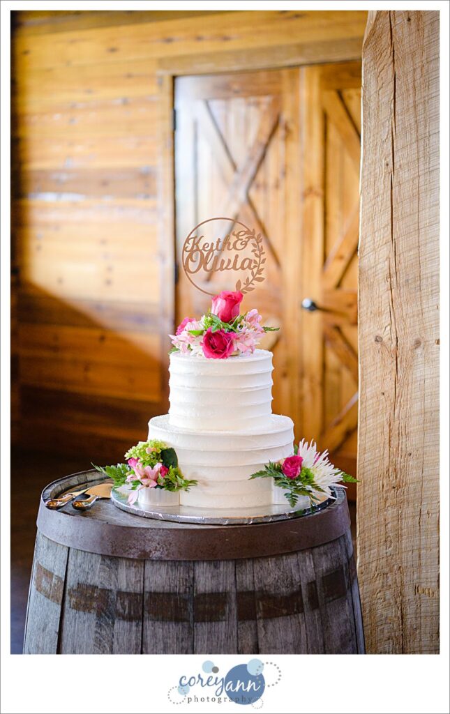 White cake with pink flowers and greenery