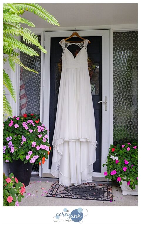 White bridal gown hanging in a doorway with flowers surrounding it