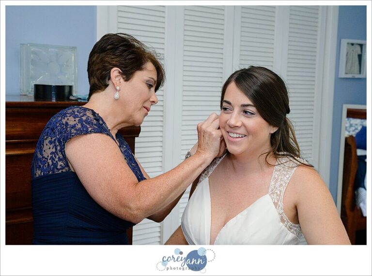 Mother helping daughter put in earrings before her wedding 