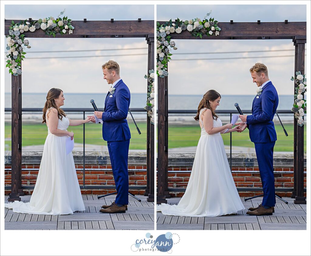 Man and woman in wedding attire standing beneath an altar overlooking Lake Erie