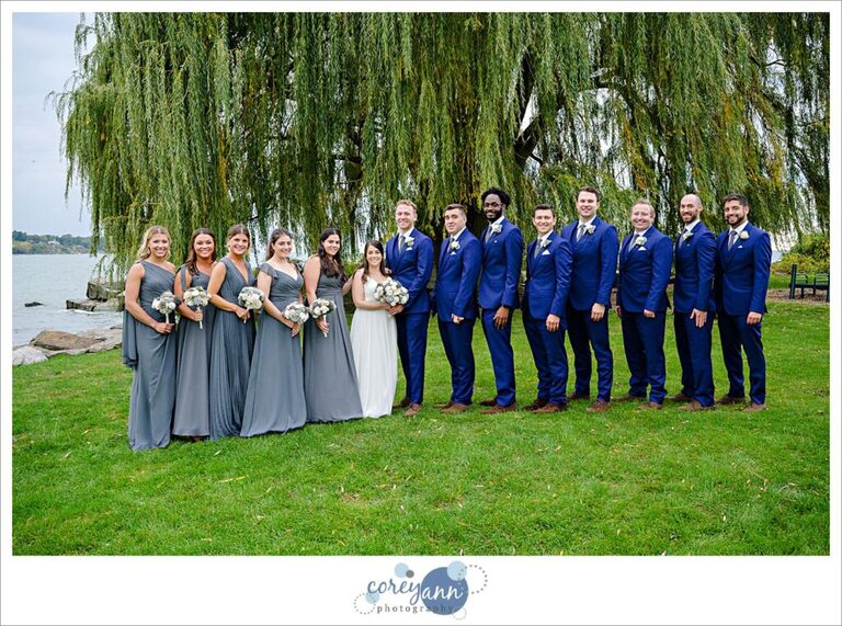 Bridal party wearing blues and greys standing near a tree at Edgewater Park in Cleveland