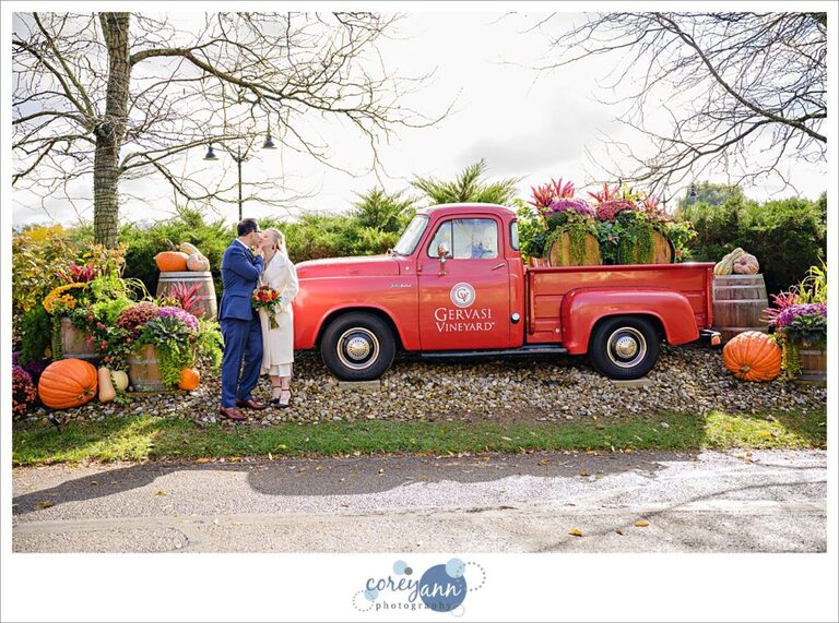 Bride and Groom posing by the Gervasi Vineyard truck decorated for the fall after their wedding.