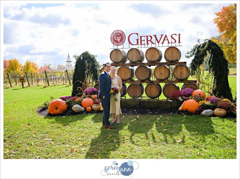 Bride and Groom standing near the Gervasi Vineyard wine barrels on their wedding day.